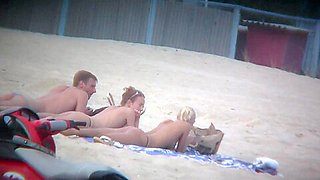 Thrilling nude friends are relaxing on a nudist beach