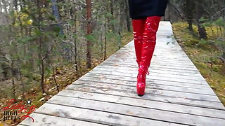Lady L sexy walking with extreme red boots in forest.
