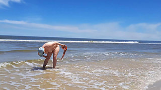 Amateur filming. A nudist plays with waves on the ocean shore.