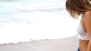 Brown haired gal in bathing suit does a beach tease